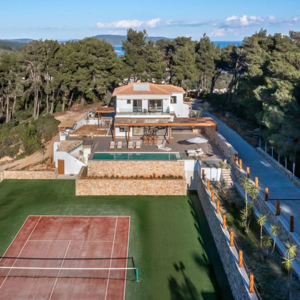A bird's-eye view of Ikos Calma with its tennis court, pool, and secluding pine trees.