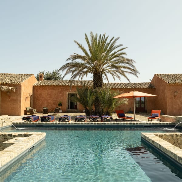 A T-shaped pool, a shady palm tree, burnt orange walls and terracotta roofs: welcome to Arbolì.