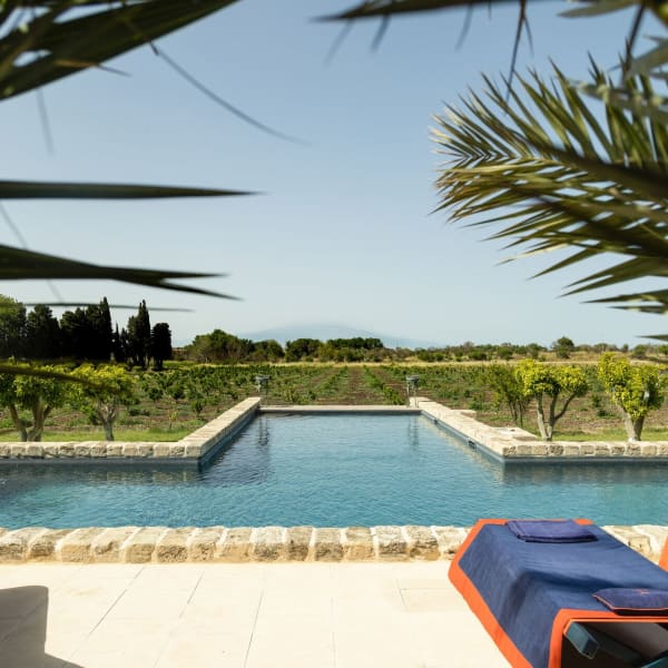 The pool is perfectly aligned with the cone of Mount Etna rising on the horizon.