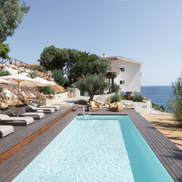 Vela's gorgeous pool area with the house and the sea in the background.