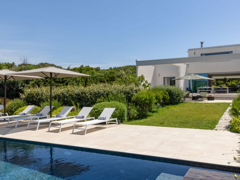 Sintineddu's clean white lines rising discreetly above the sea-facing gardens and the pool.