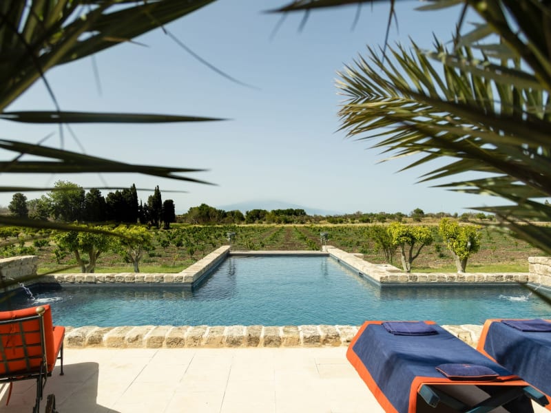 The pool is perfectly aligned with the cone of Mount Etna rising on the horizon.