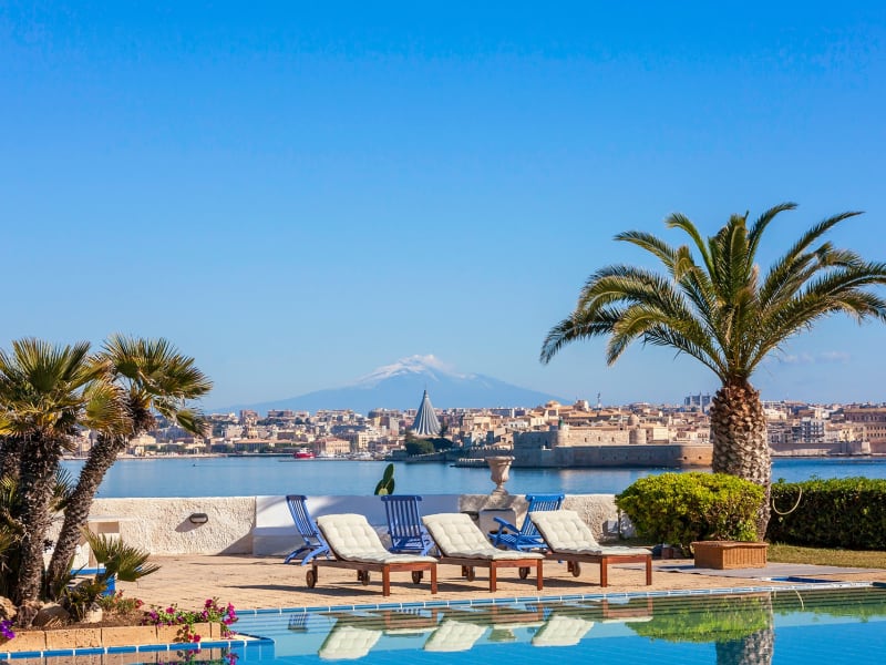 Relaxing by the pool with Syracuse and Mount Etna in the background.
