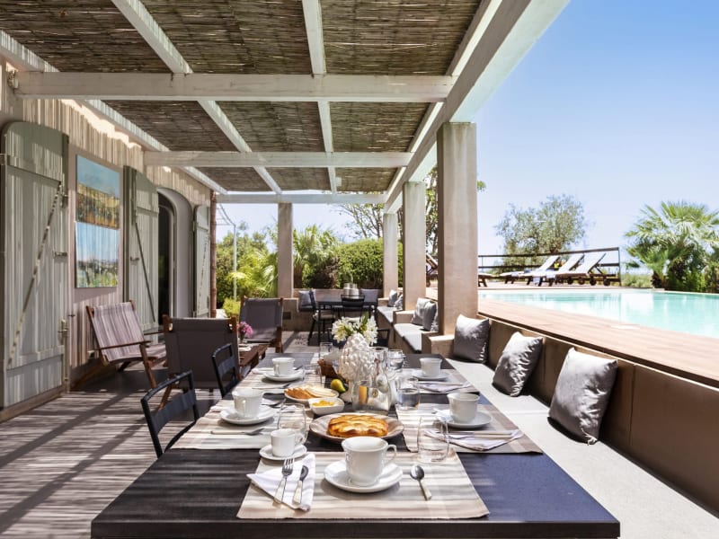 The poolside terrace is furnished for dining and relaxing.