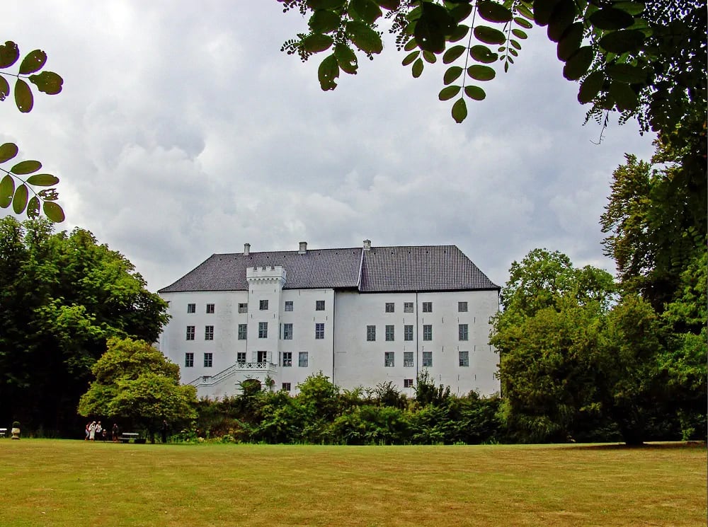 Exterior view of Dragsholm Castle, a historic and reputedly haunted castle in Denmark, surrounded by greenery. Photo by Bococo. Exterior view of Dragsholm Castle, a historic and reputedly haunted castle in Denmark, surrounded by greenery. Photo by Bococo.