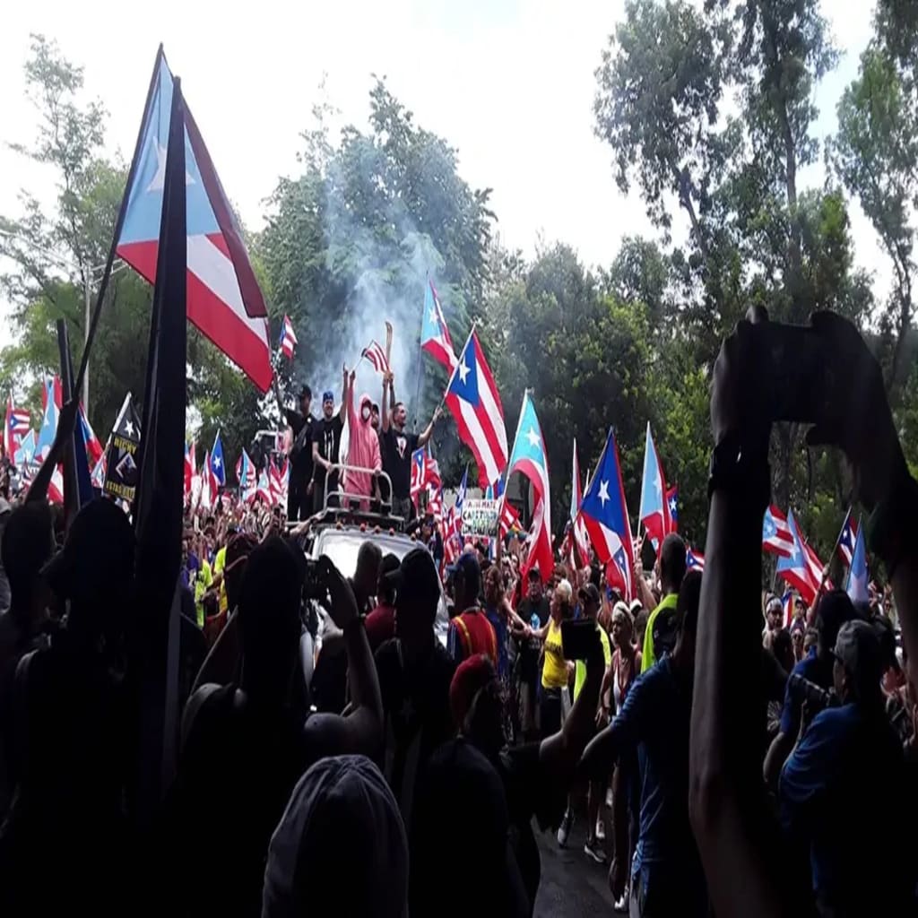 Protesters celebrating the resignation of Ricardo Rosselló in San Juan, the day after the announcement. Residente, Bad Bunny and Ricky Martin (center, L–R) were among many public figures that demanded Rosselló's resignation. Photo by Daryana Rivera. Protesters celebrating the resignation of Ricardo Rosselló in San Juan, the day after the announcement. Residente, Bad Bunny and Ricky Martin (center, L–R) were among many public figures that demanded Rosselló's resignation. Photo by Daryana Rivera.