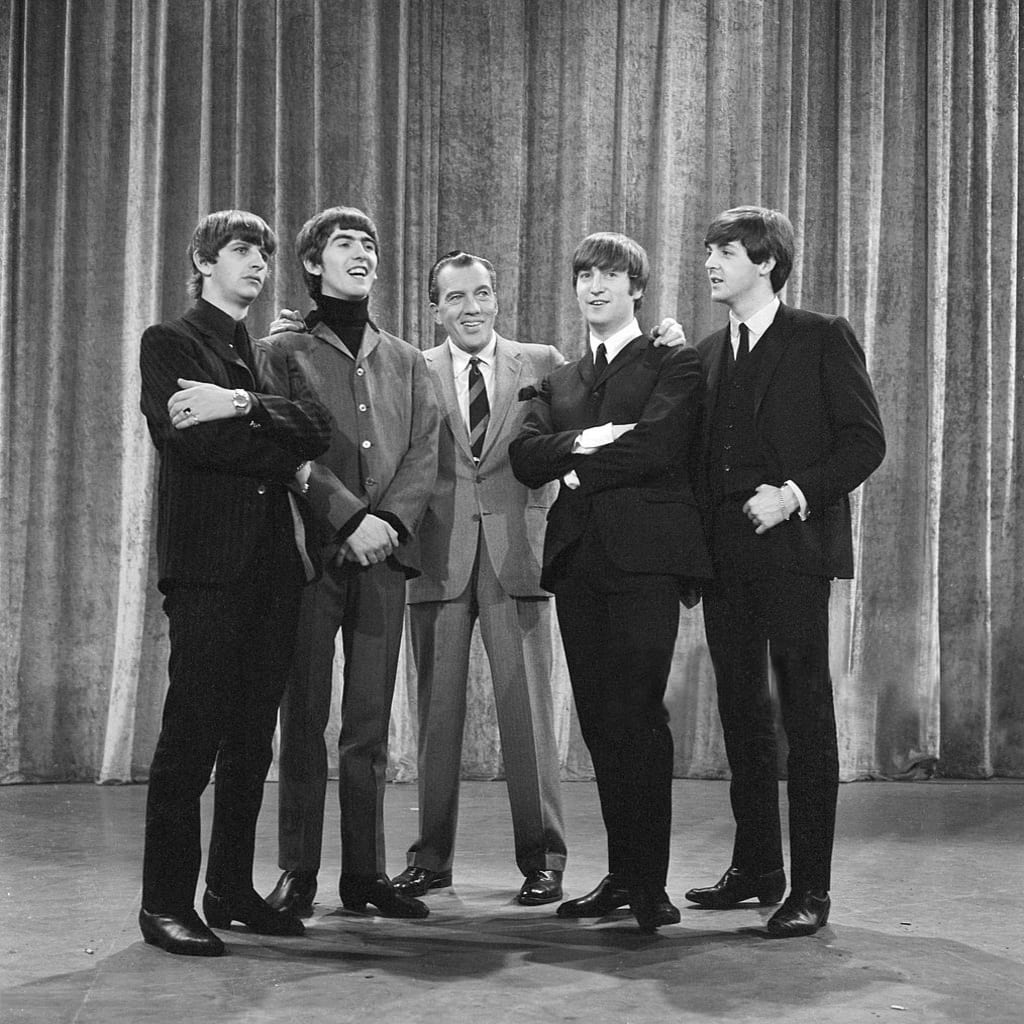 Photo of The Beatles with Ed Sullivan from their first appearance on Sullivan's US variety television program in February 1964. From left: Ringo Starr, George Harrison, Ed Sullivan, John Lennon, Paul McCartney. Public domain. Photo of The Beatles with Ed Sullivan from their first appearance on Sullivan's US variety television program in February 1964. From left: Ringo Starr, George Harrison, Ed Sullivan, John Lennon, Paul McCartney. Public domain.