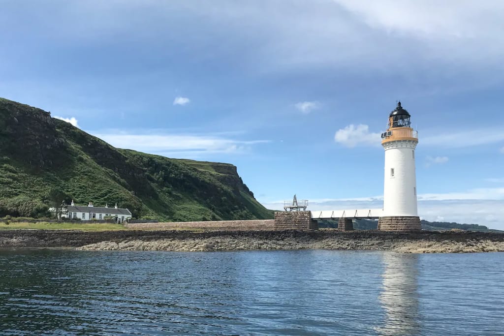 A coastal lighthouse and adjacent white house offering unique Airbnb accommodation with picturesque views by the sea. Photo by host Alexa/Airbnb. A coastal lighthouse and adjacent white house offering unique Airbnb accommodation with picturesque views by the sea. Photo by host Alexa/Airbnb.
