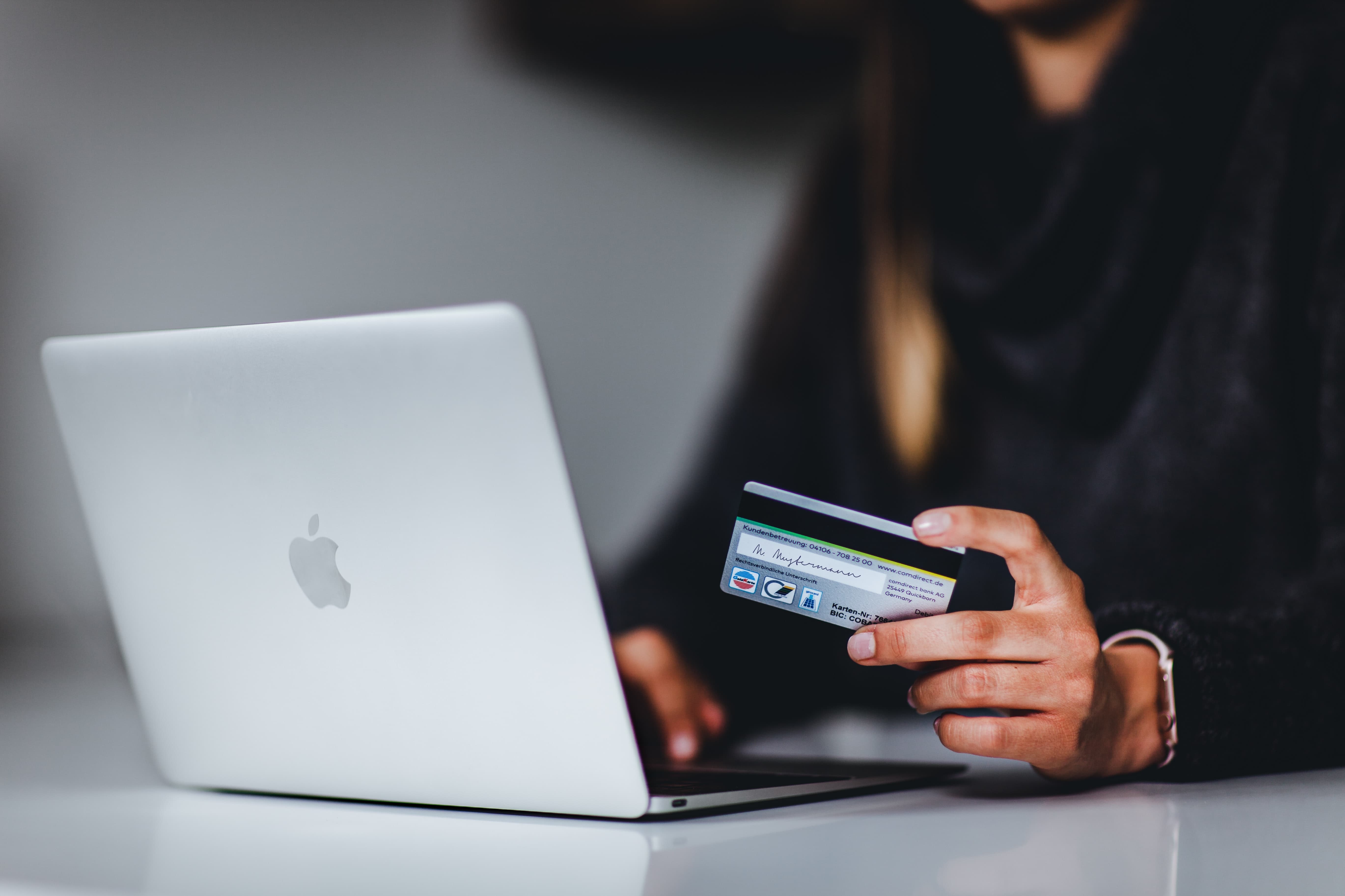 Woman holding credit card next to laptop about to buy something online