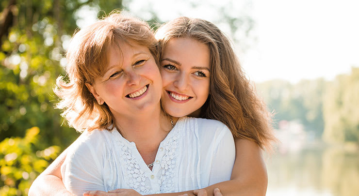 A mãe e a filha abraçando e sorrindo após a redução da campânula clitorial.