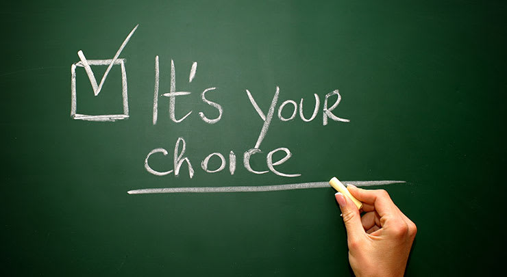 Woman writing It's your choice on a chalkboard.