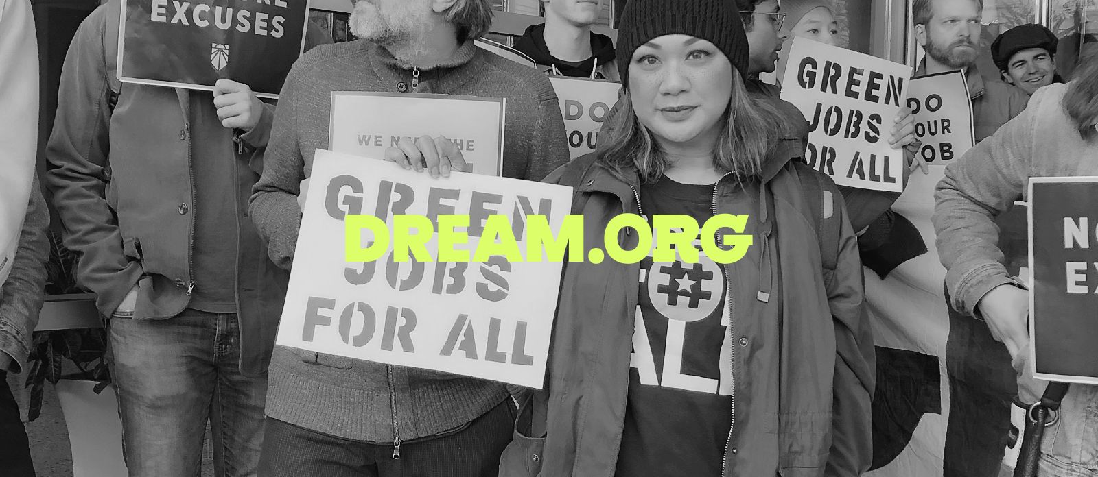 Woman at a protest holding a sign that says “Green Jobs for All”