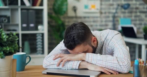 Portrait of young man employee sleeping on desk in office relaxing at work. Photo by Vitaly Gariev on Unsplash