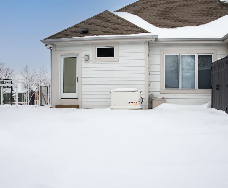 Generac generator outside a house in the snow 