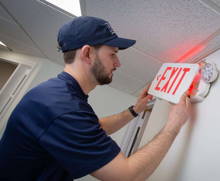 Commercial electrician installing exit sign