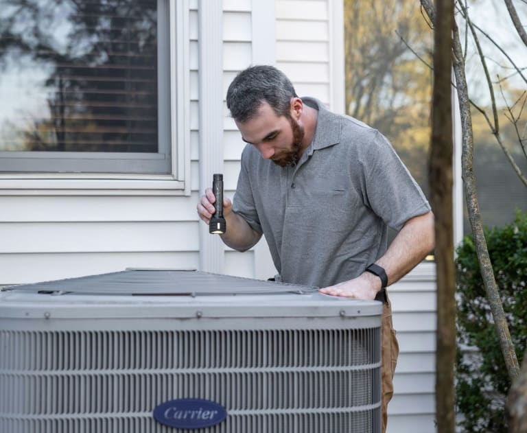Electricians near me work with HVAC installers outside a house on an AC unit