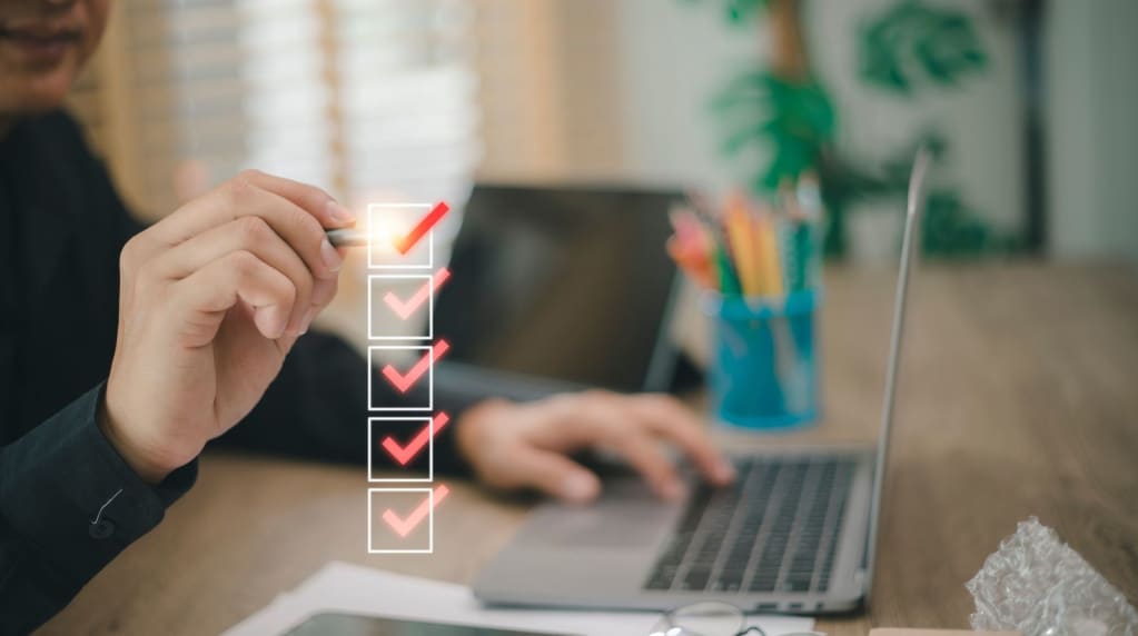 Person with electrical safety checklist and computer