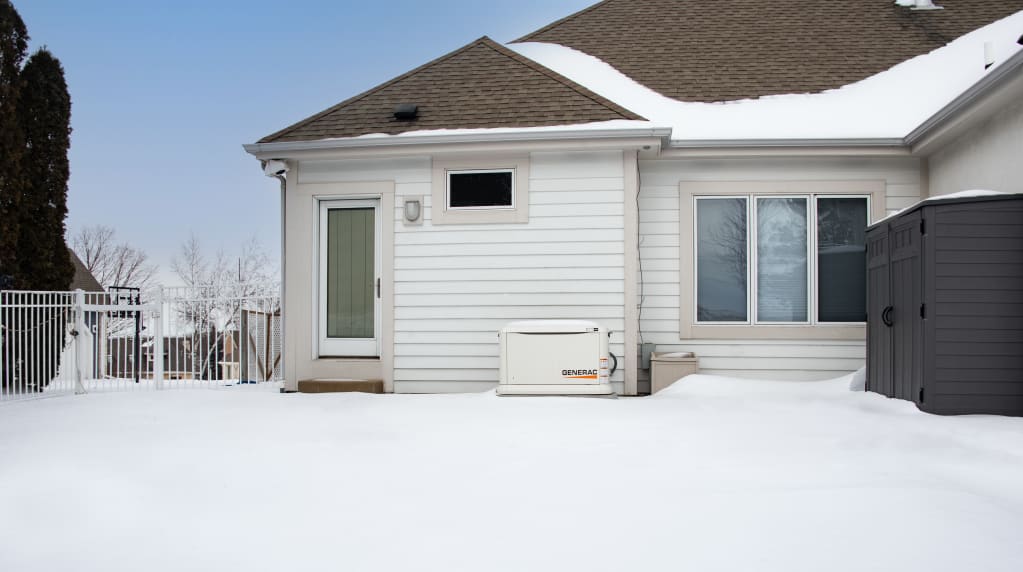 Generac generator outside a house in the snow 