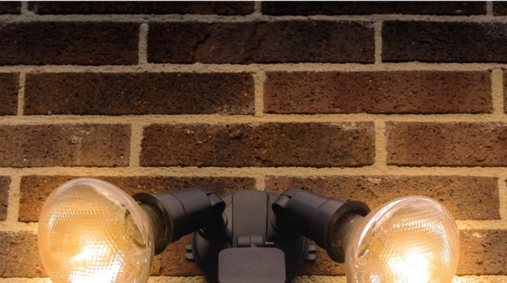 Two lights and a motion sensor on an exterior brick wall