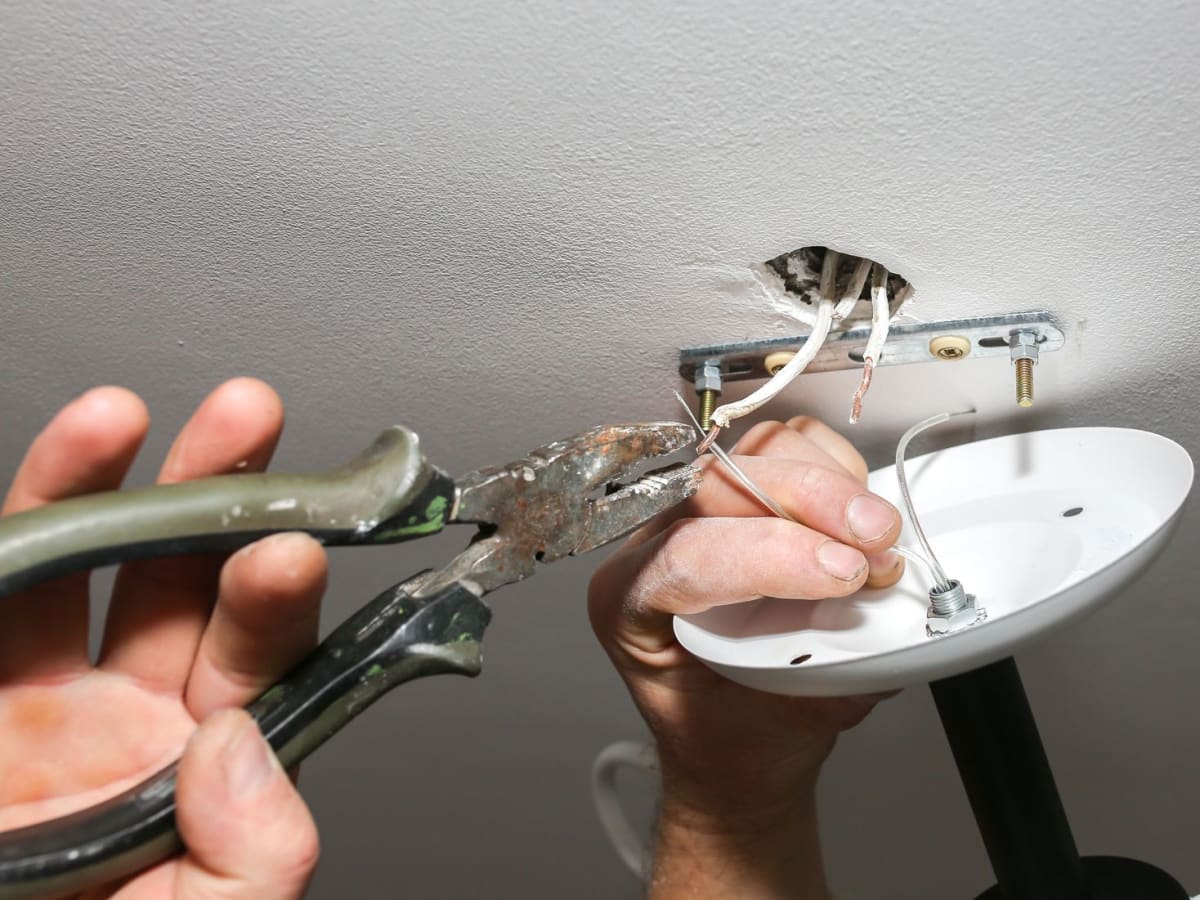 Electrician using rusty pliers on a wire in a light