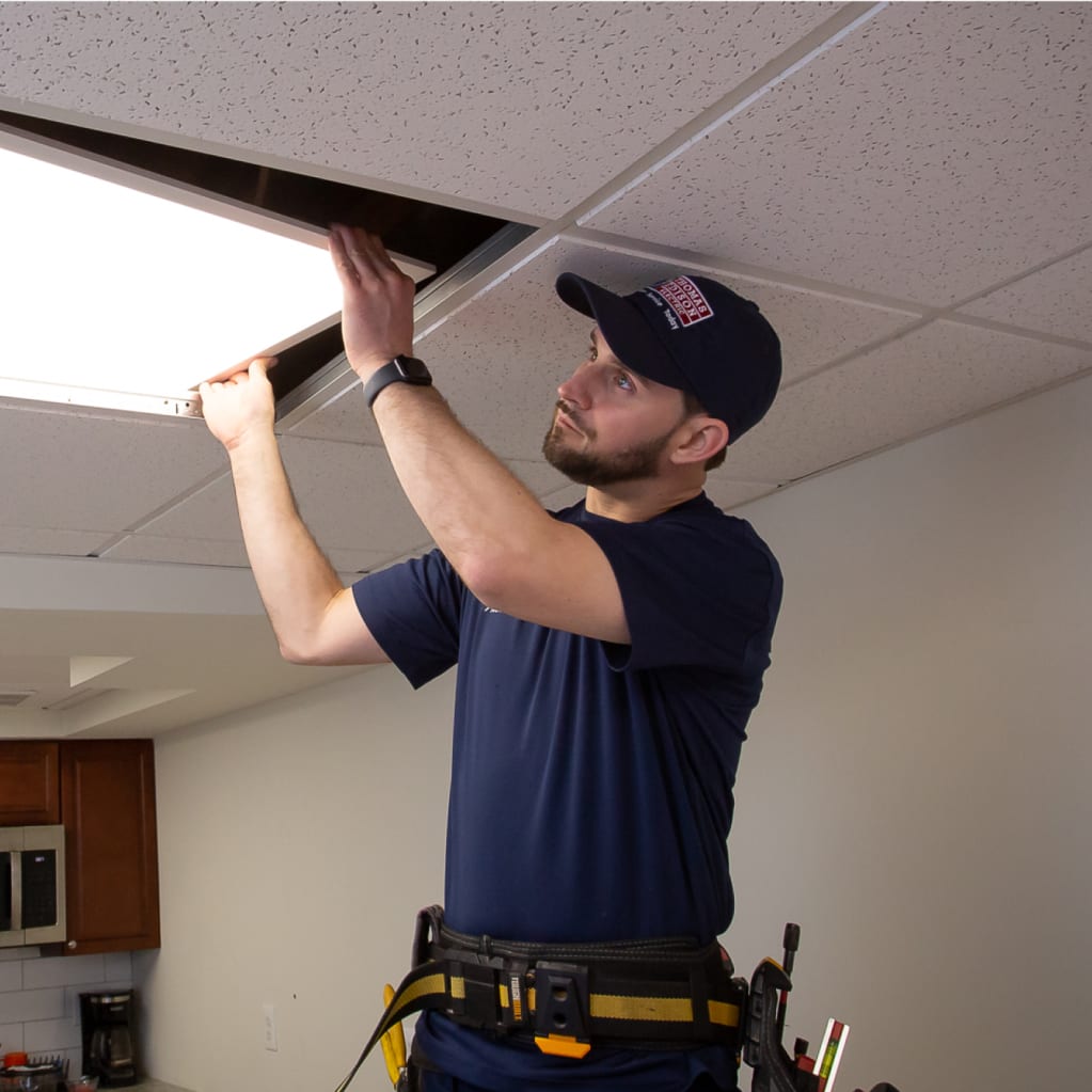 Electrician replacing or repairing an LED ceiling light panel