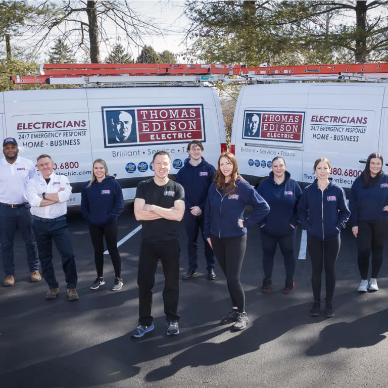 Thomas Edison Electric team standing near their work trucks