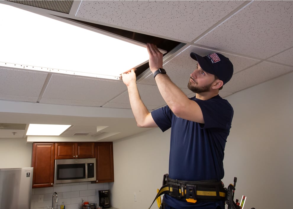 Electrician replacing or repairing an LED ceiling light panel