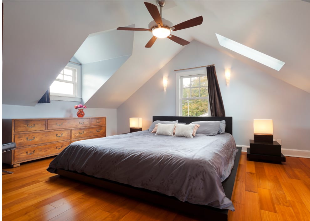 Ceiling fan over a bed in an attic space bedroom