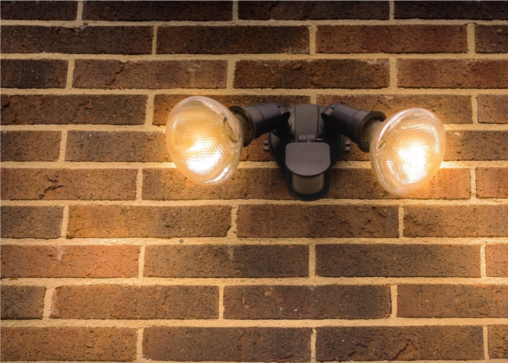 Two lights and a motion sensor on an exterior brick wall