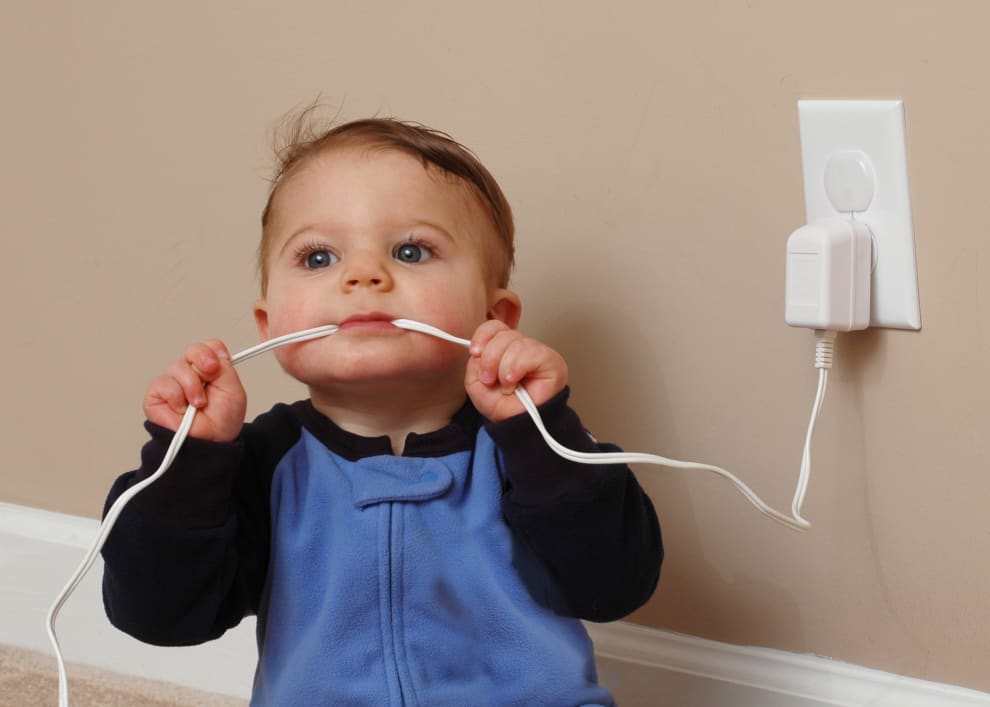 A baby dangerously chewing on an electrical cord