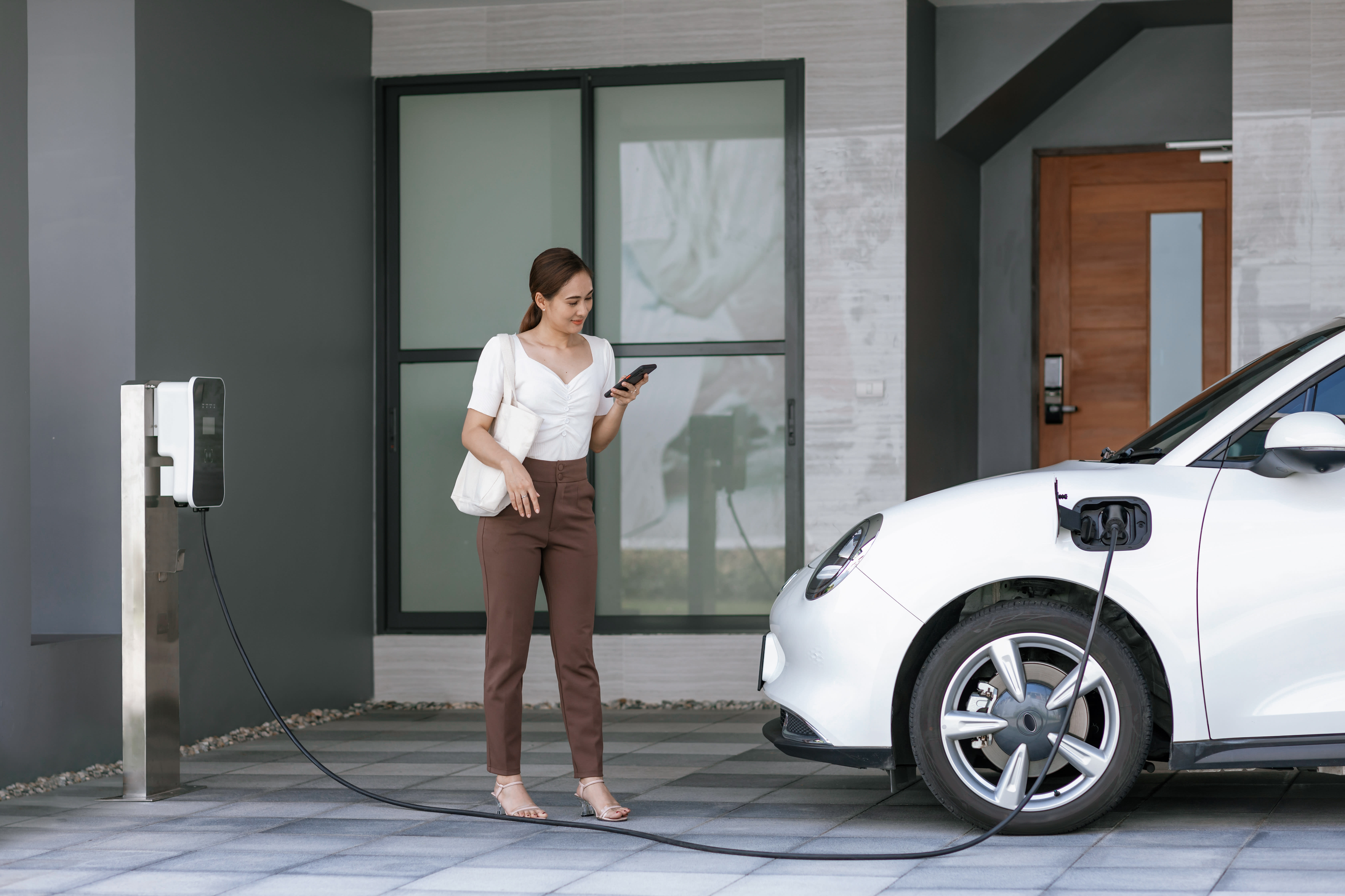 Woman with EV vehicle near EV charger
