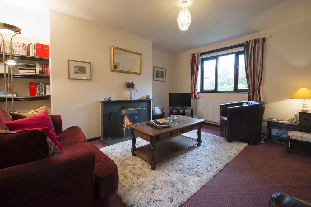 Photo of a living room with a red carpet, chairs, and a fireplace