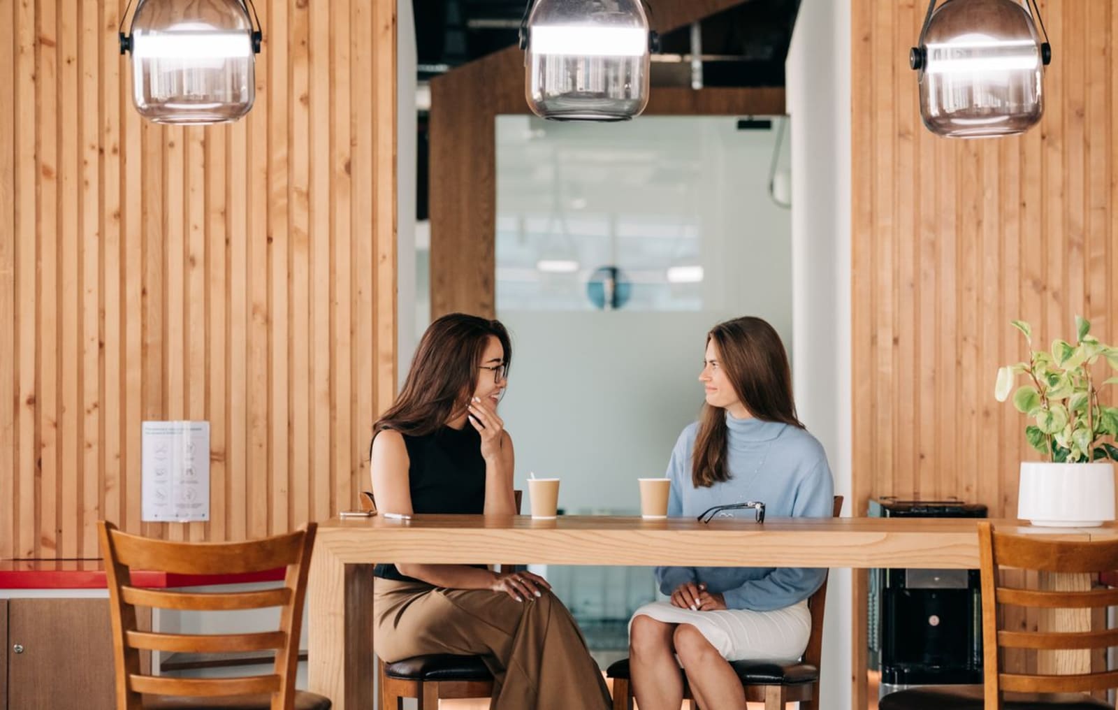 Friends laughing together over coffee at a table in a café.
