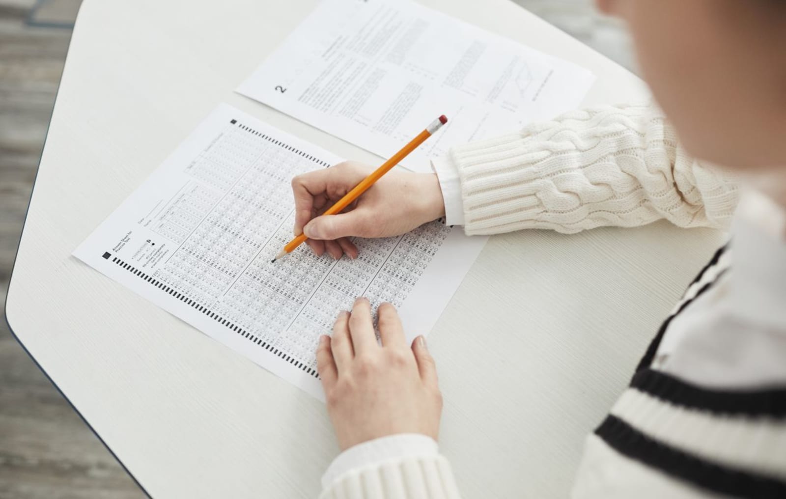 A student filling in a multiple-choice placement test with a pencil at a desk.