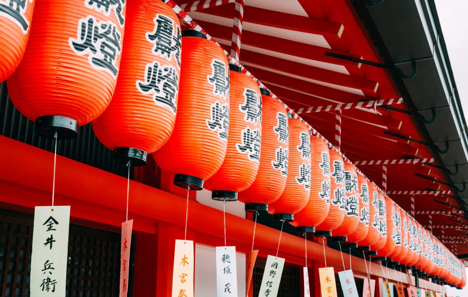 A row of glowing red Japanese lanterns hanging at a shrine.