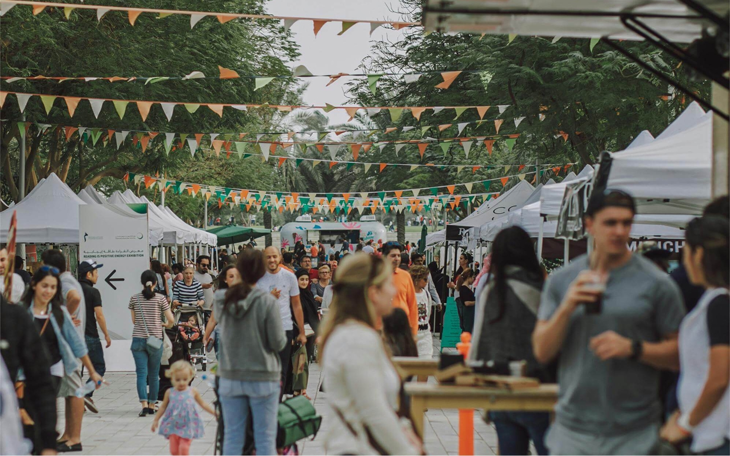 Busy market with people walking around, stalls and party bunting