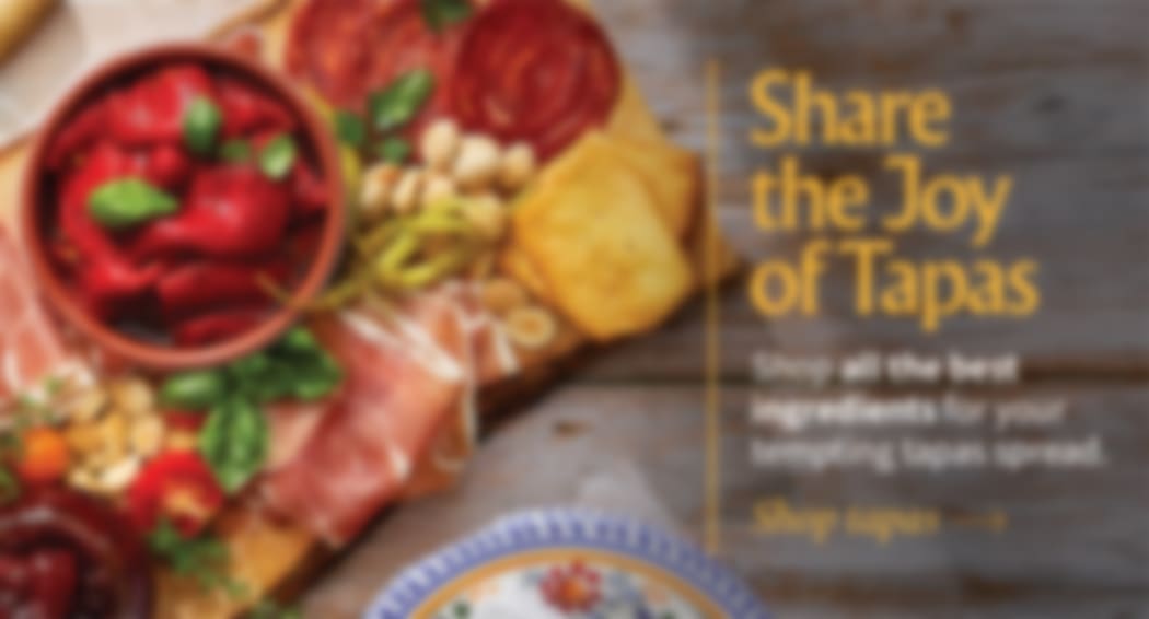Sliced Jamon in a plate with some olives and a knife out of focus