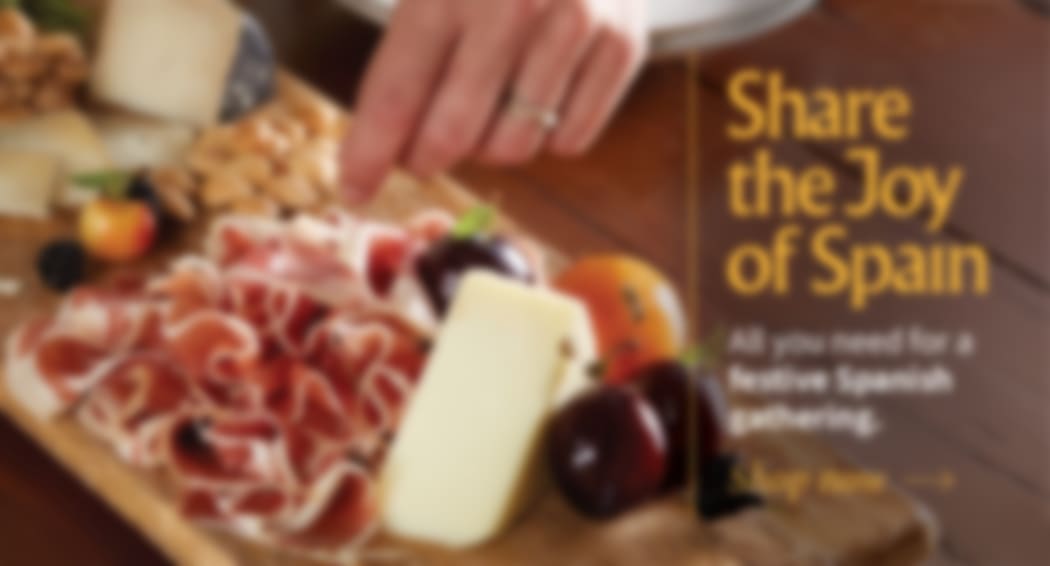 Sliced Jamon in a plate with some olives and a knife out of focus