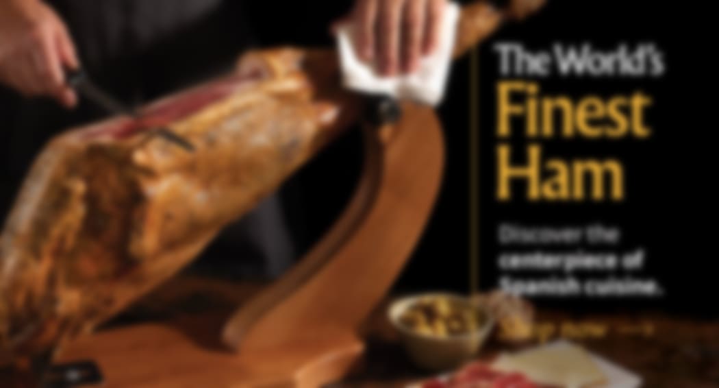 Sliced Jamon in a plate with some olives and a knife out of focus