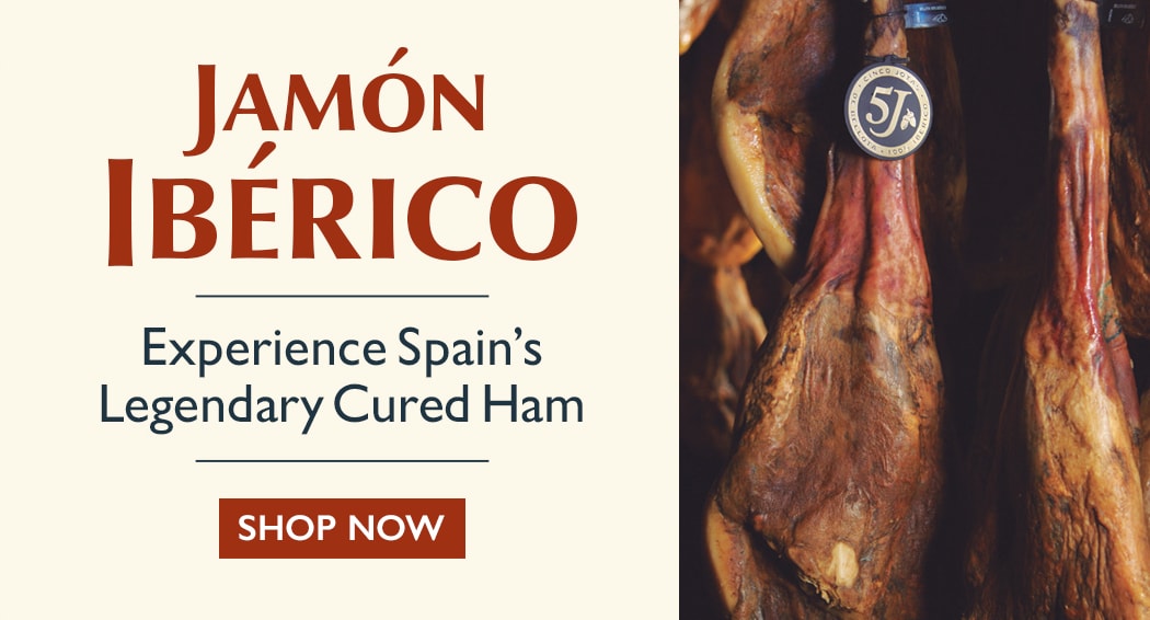 Sliced Jamon in a plate with some olives and a knife out of focus