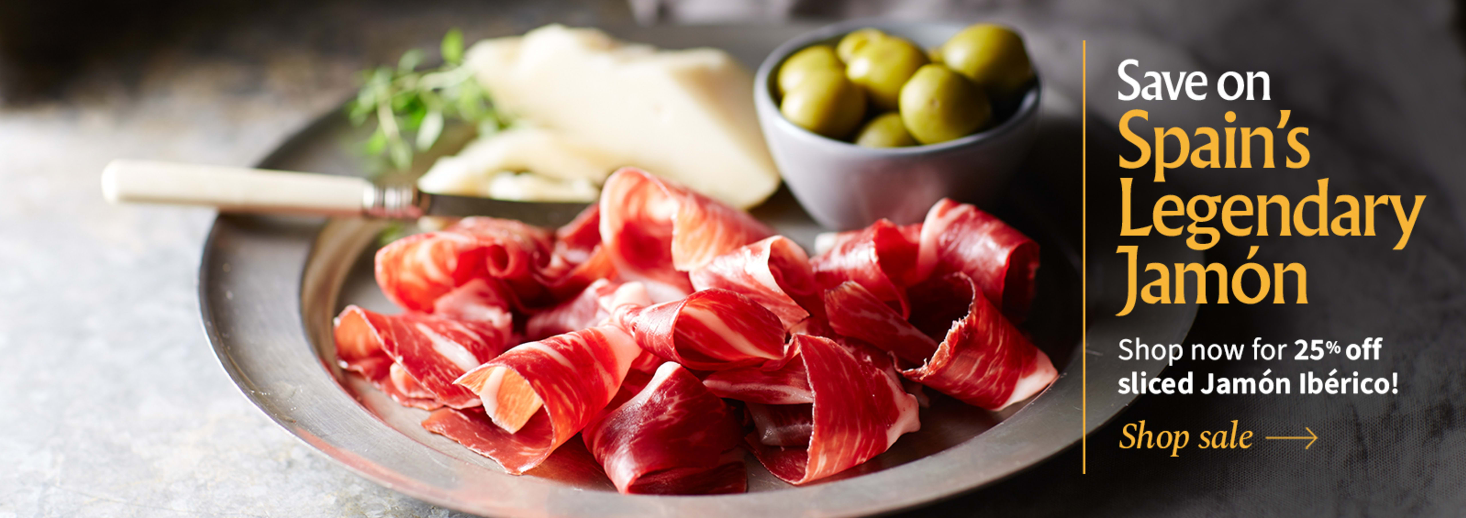 Sliced Jamon in a plate with some olives and a knife out of focus