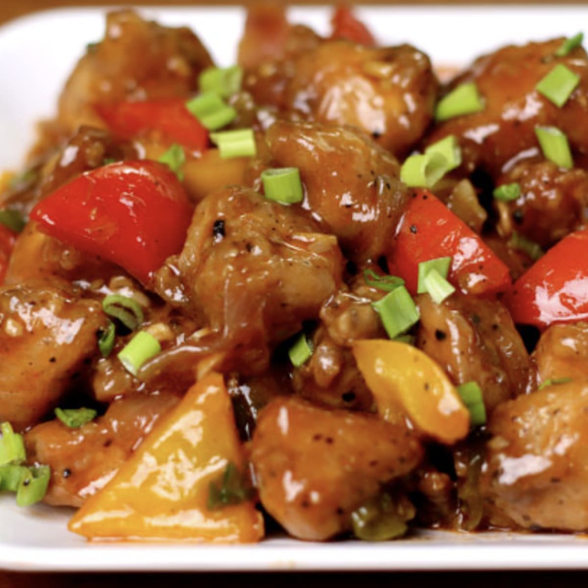 Chilli Chicken with green peppers and spring onion on a black platter