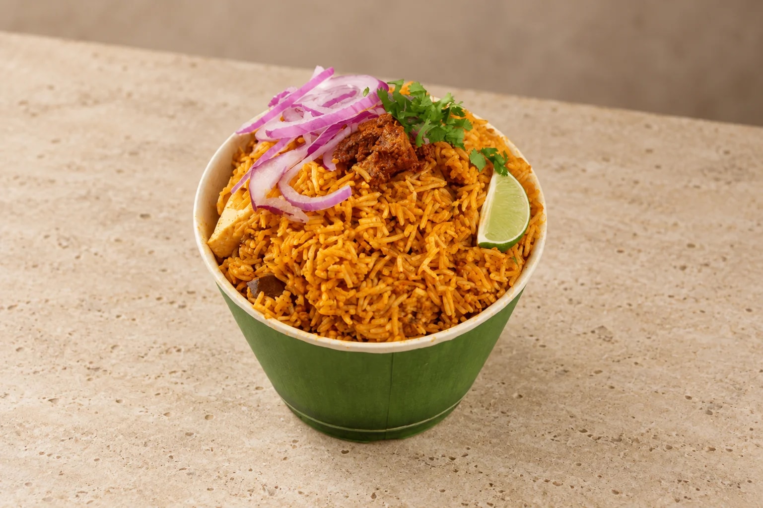 Hyderabadi goat dum biryani in a brass handi with fresh coriander, whole spices and fried onions