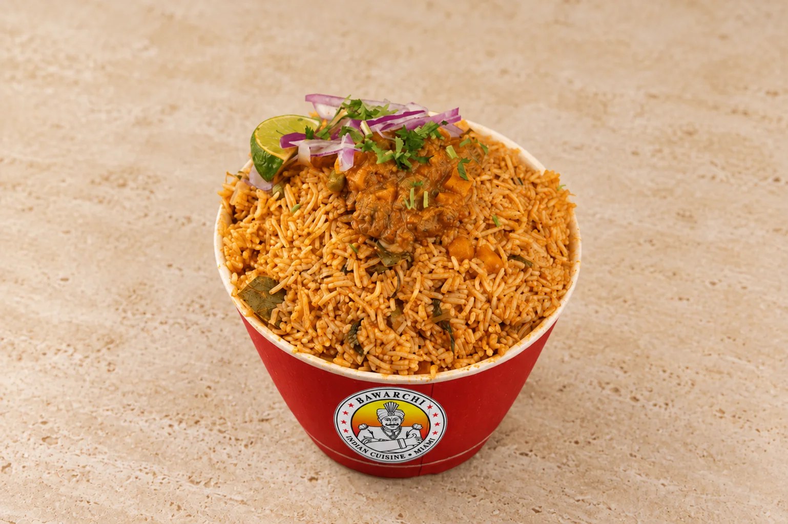 Hyderabadi goat dum biryani in a brass handi with fresh coriander, whole spices and fried onions