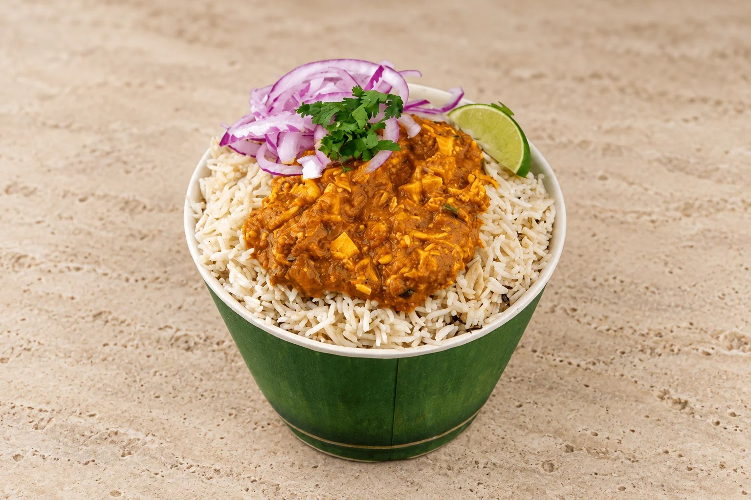 Hyderabadi goat dum biryani in a brass handi with fresh coriander, whole spices and fried onions