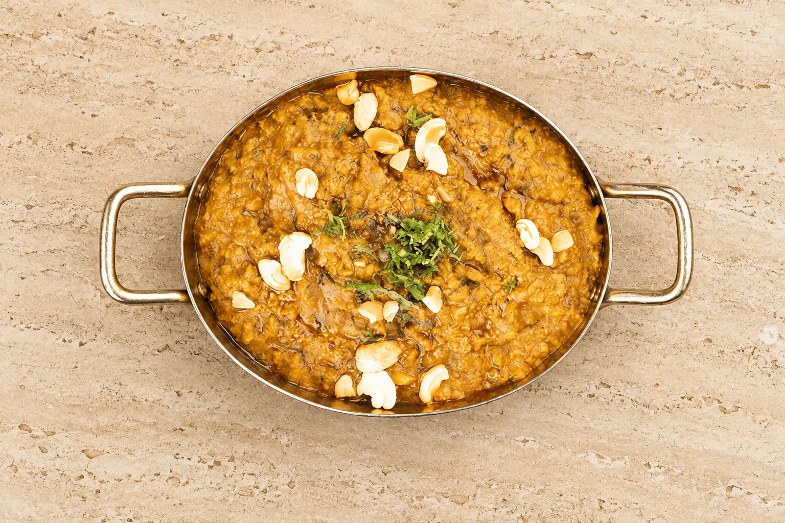 Hyderabadi goat dum biryani in a brass handi with fresh coriander, whole spices and fried onions