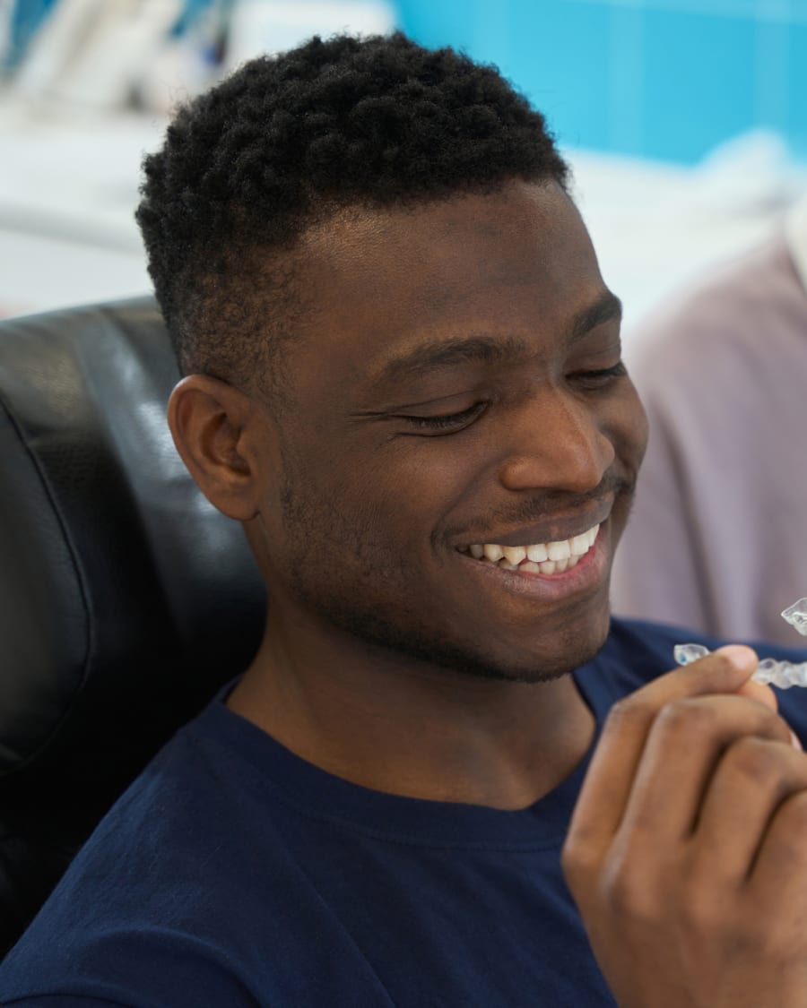 Young man holding a clear Invisalign® aligner with his orthodontist