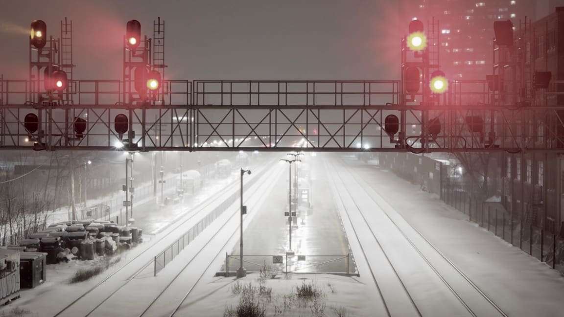 Red train lights over snowy tracks next to Wallace St Bridge, Toronto, ON.