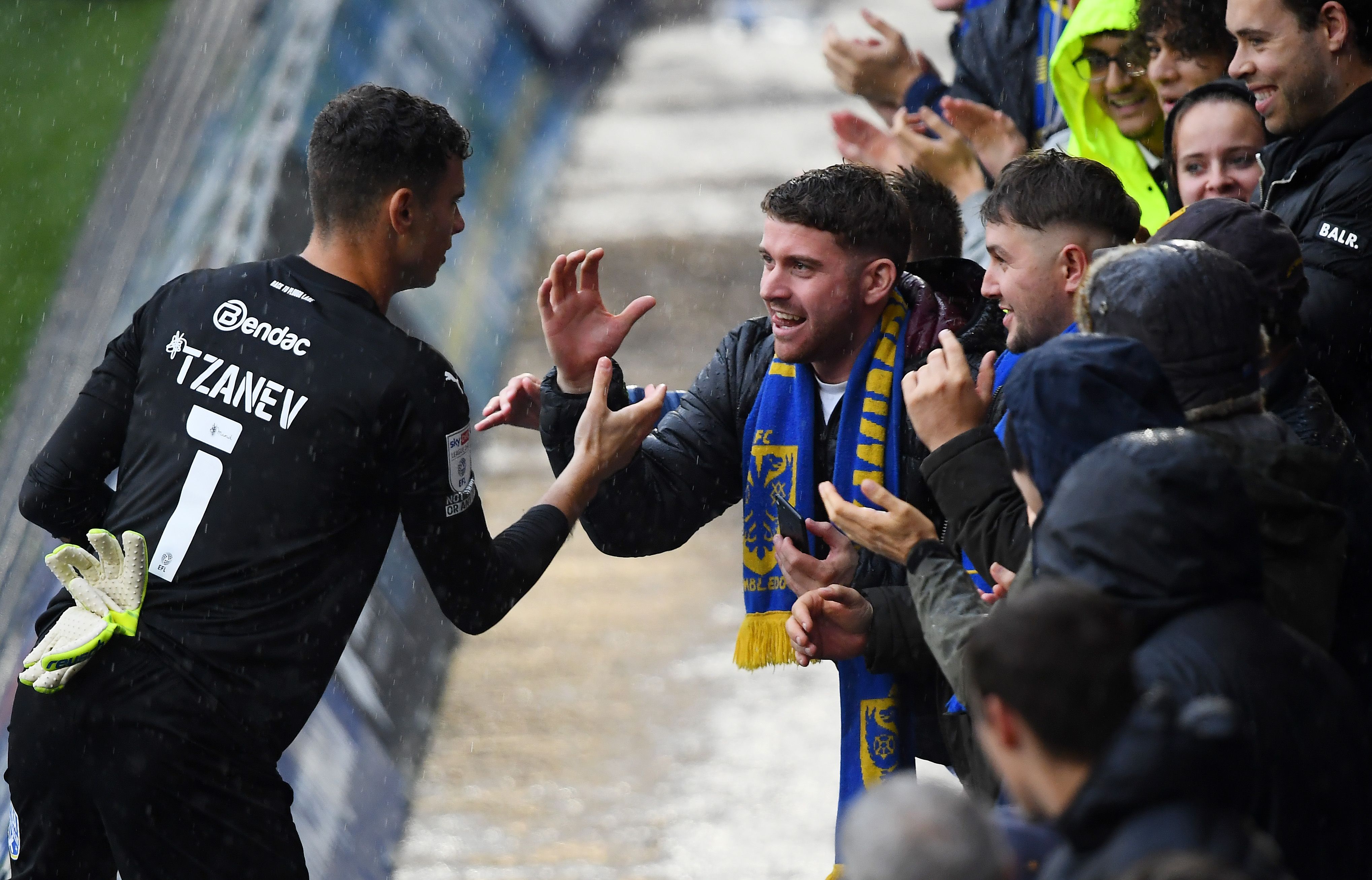 Wimbledon goalkeeper Nik Tzanev hi-fives a Wimbledon fan