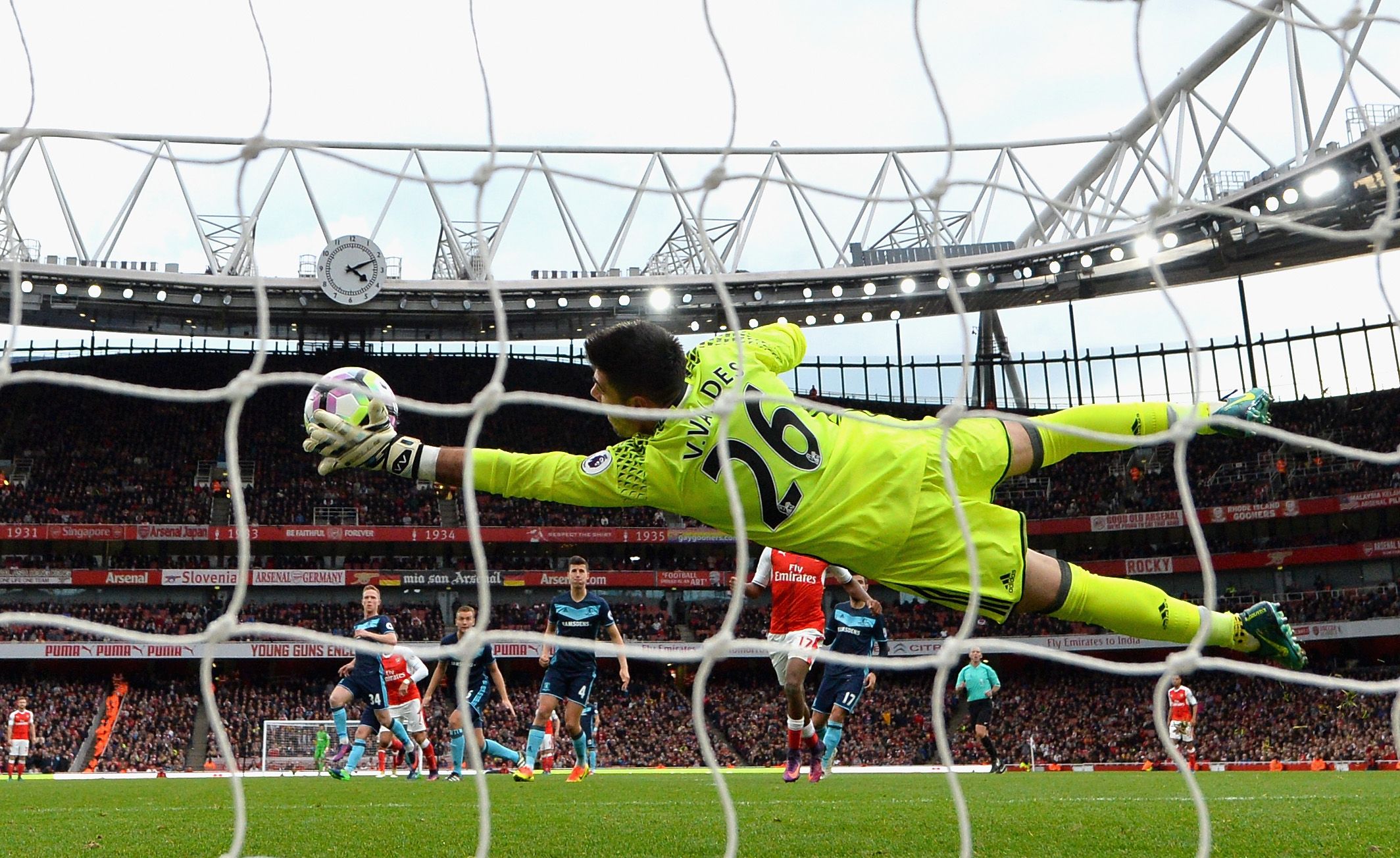 Victor Valdes makes a diving save to his left wearing a yellow kit for Middlesbrough vs Arsenal (Goalkeeper.com)